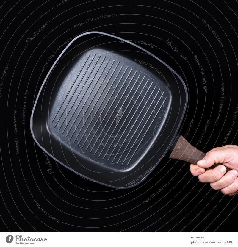 Hand hält eine schwarze, leere, quadratische Grillpfanne. Pfanne Küche Restaurant Beruf Mann Erwachsene Gußeisen Kaukasier Küchenchef Koch Essen zubereiten