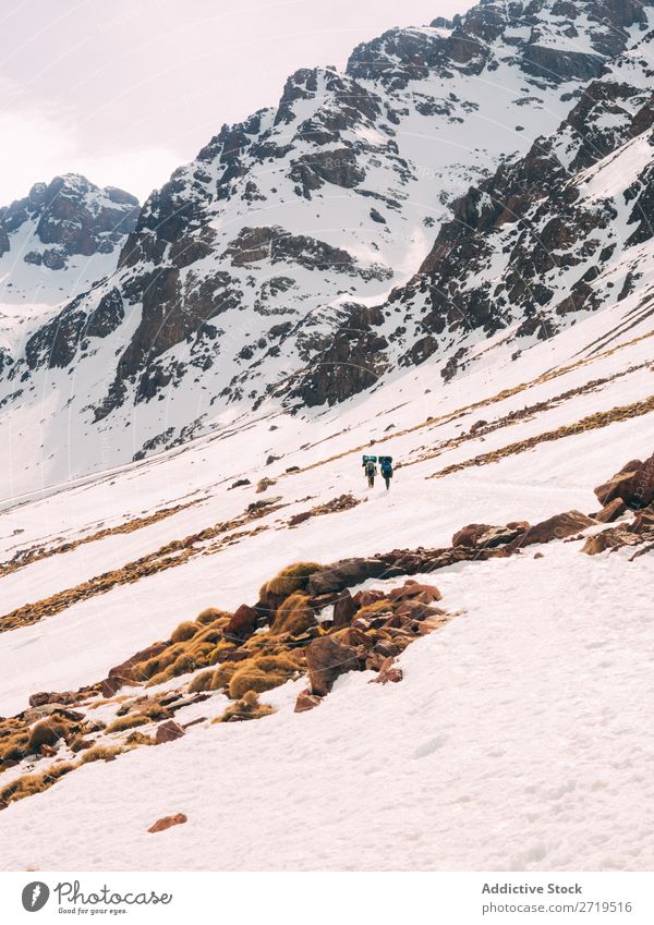 Menschen, die auf einem verschneiten Hang der Berge wandern. Berge u. Gebirge Tourismus Winter Landschaft Felsen Trekking Schnee Wege & Pfade laufen