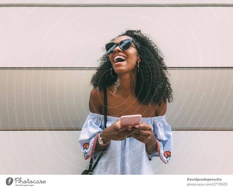 Fröhliche schwarze Frau mit Handy Wand Erwachsene lässig PDA Afrikanisch urwüchsig Textfreiraum heiter Jugendliche Lifestyle Pastell Hintergrundbild Mitteilung