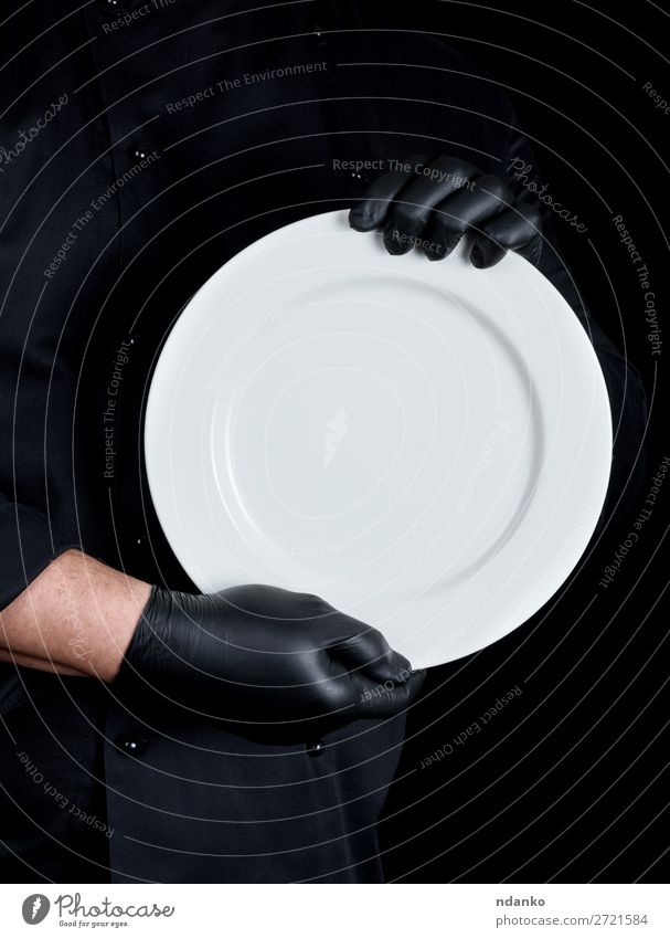 Koch in schwarzer Uniform mit einem runden leeren Teller. Küche Restaurant Beruf Mensch Mann Erwachsene Hand Handschuhe dunkel weiß Kaukasier Küchenchef
