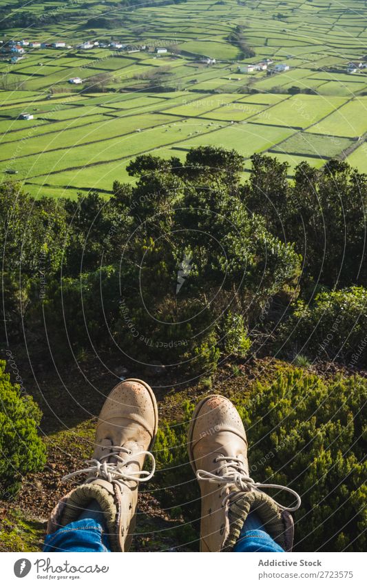 Person, die auf einem Hügel am Zaun sitzt. Feld grün Aussicht Natur Wiese Beine Schuhe Gras Landschaft ländlich Sommer Pflanze Azoren Frühling Rasen Landen