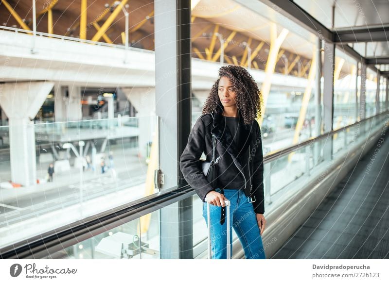 schwarze Frau auf dem Fahrsteig am Flughafen mit einem rosa Koffer. schön Afrikanisch Amerikaner Bewegung Gang Rolltreppe Ausflug Station Gepäck laufen Richtung