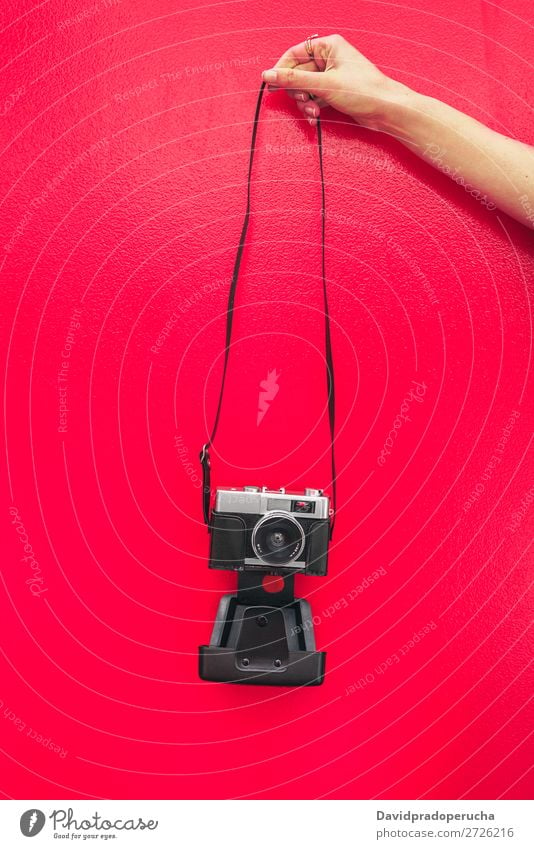 Hand haltend eine Vintage-Kamera isoliert an der roten Wand Arme Fotokamera altehrwürdig rosa retro vereinzelt Studioaufnahme Halt Freizeit & Hobby