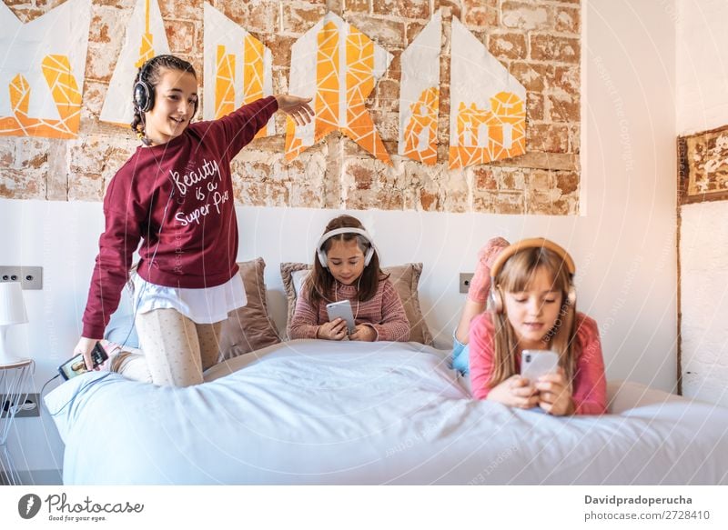 Drei Schwestern spielen miteinander und liegen zu Hause im Bett und hören Musik. Schlafzimmer Mädchen Glück Familie & Verwandtschaft weiß gemütlich Jugendliche