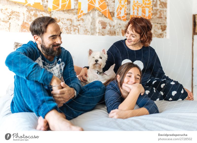 Ein Paar entspannt zu Hause im Bett mit seiner kleinen Tochter und dem Hund. Zuneigung Schlafzimmer Ehefrau Ehemann Kind Haustier Welpe Mama Papa Eltern Vater