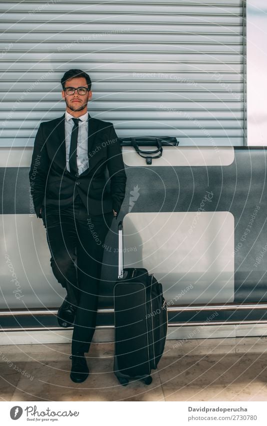 Junger Geschäftsmann steht mit dem Koffer am Flughafen und wartet auf den Flug. Mann Ferien & Urlaub & Reisen Business warten Flugzeug Tor im Ausland Gebäude