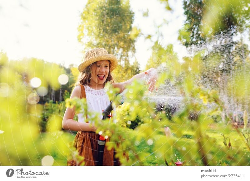 fröhliches Kind Mädchen Blumen gießen mit Schlauch im Sommergarten Lifestyle Freizeit & Hobby Garten Gartenarbeit Natur Landschaft Pflanze Frühling Lächeln