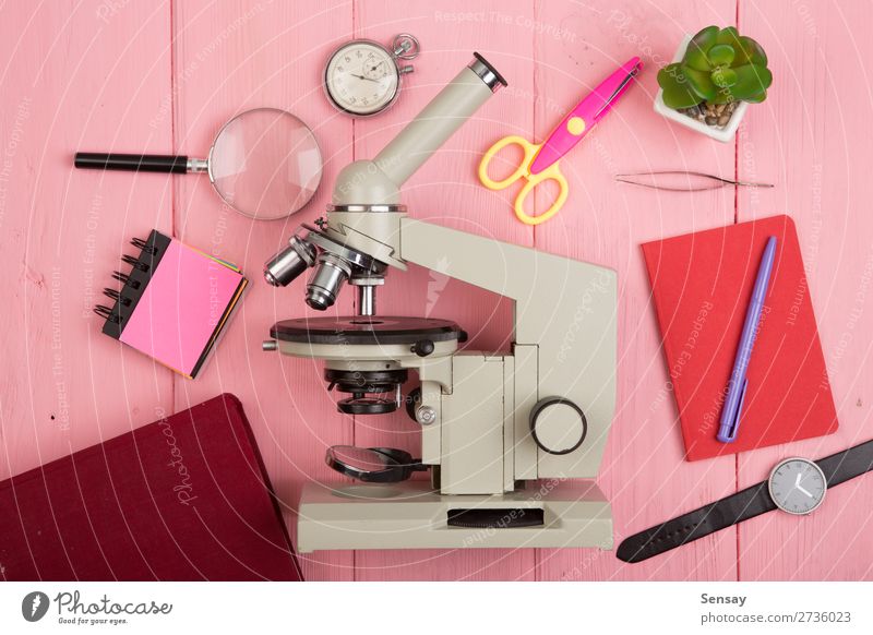 Bildungskonzept - Notizblock, Mikroskop auf dem rosa Holztisch Schreibtisch Tisch Wissenschaften Schule lernen Klassenraum Tafel Studium Labor Buch Bibliothek