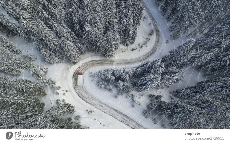 Luftlandschaft mit mäandrierender verschneiter winterlicher Bergstraße mit einem fahrenden Lastwagen Winter Schnee Berge u. Gebirge Natur Landschaft Baum Wald