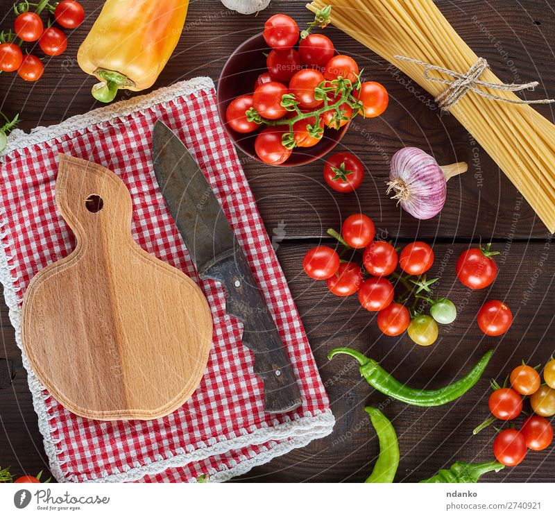 Schneidebrett mit Messer und frischen roten Kirschtomaten Gemüse Ernährung Mittagessen Vegetarische Ernährung Tisch Küche Holz Linie Essen groß lang oben braun