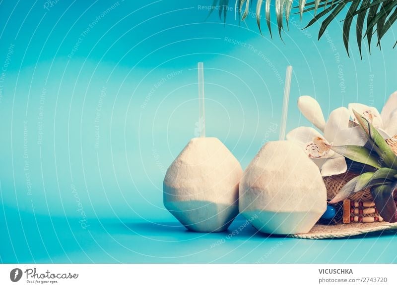 Frischer tropischer Kokosnuss-Cocktail mit Trinkhalmen und Palmblättern und Blumen auf blau-türkisem Hintergrund. Tropischer Sommerurlaub, Reise- und Ferienkonzept