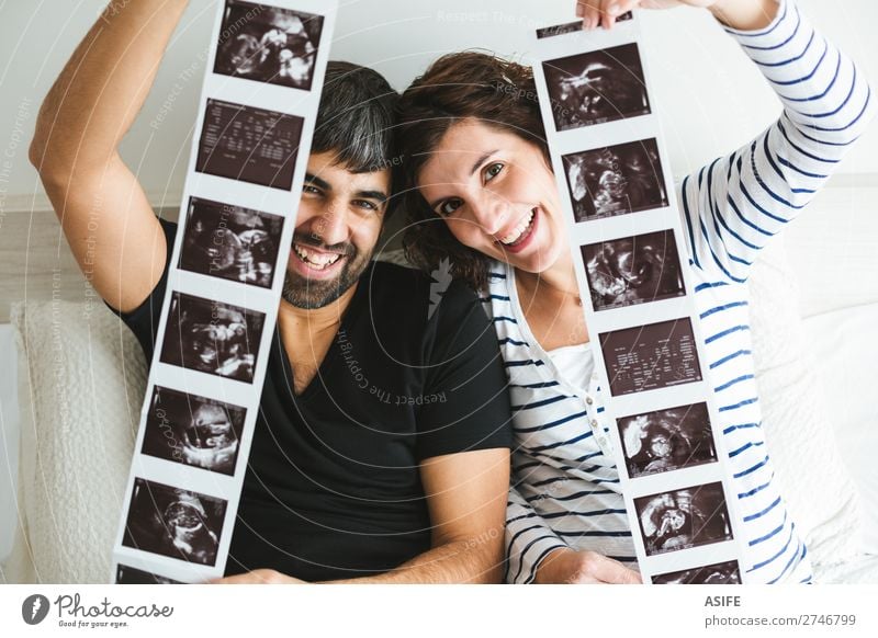 Glückliches schwangeres Paar, das Ultraschallbilder seines Babys zeigt. schön Leben Frau Erwachsene Mann Eltern Mutter Vater Familie & Verwandtschaft Lächeln
