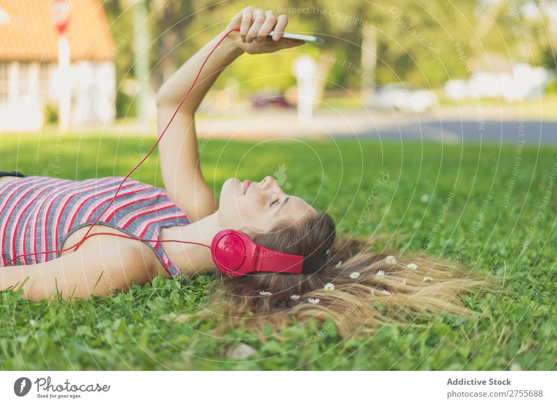 Mädchen mit Gadgets auf dem Rasen Frau Kopfhörer Erholung PDA feminin Musik träumen Blume Wiese Entertainment Schüler Park Sommer Freiheit Zufriedenheit Natur