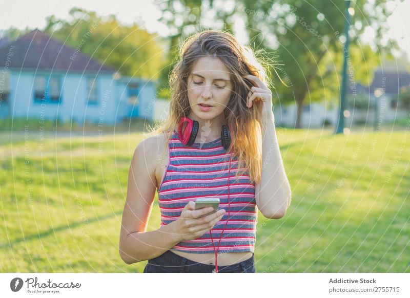 Stylisches Mädchen, das mit Gadgets posiert. Frau PDA Körperhaltung Erholung Sommer Natur Kopfhörer feminin Musik Zufriedenheit träumen Wiese Halt Gerät