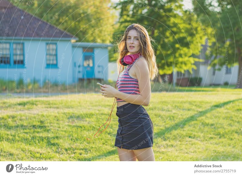 Stylisches Mädchen, das mit Gadgets posiert. Frau PDA Körperhaltung Erholung Sommer Natur Kopfhörer feminin Musik Zufriedenheit träumen Wiese Halt Gerät