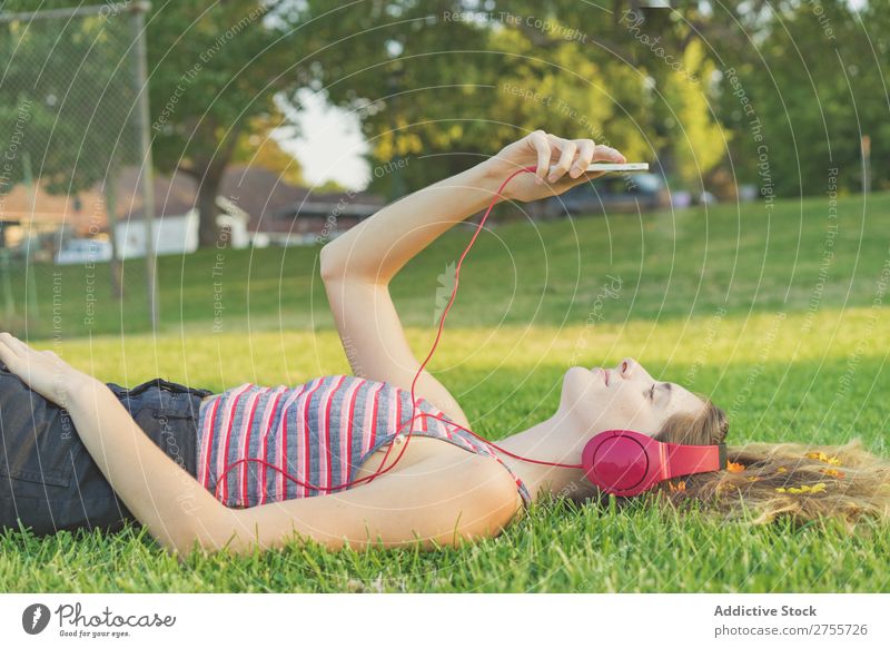Mädchen mit Gadgets auf dem Rasen Frau Kopfhörer Erholung PDA feminin Musik träumen Blume Wiese Entertainment Schüler Park Sommer Freiheit Zufriedenheit Natur