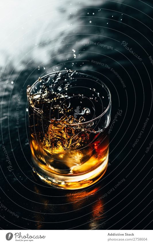 Ein Glas spritzender Whiskey Alkohol Getränk Bourbon braun Cocktail kalt Coolness Kristalle Würfel dunkel trinken Tropfen elegant Vogelperspektive Glaswaren Eis