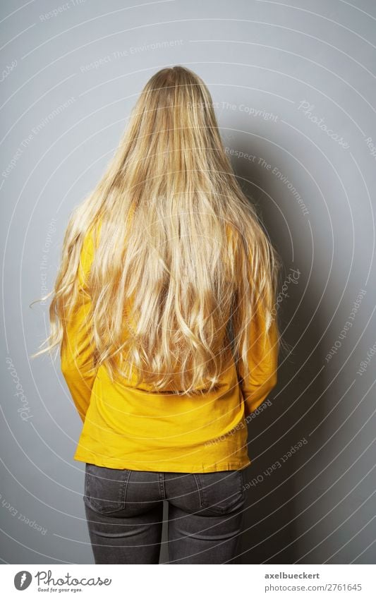 Frau mit langen blonden Haaren von hinten Mensch feminin Junge Frau Jugendliche Erwachsene 1 13-18 Jahre 18-30 Jahre Mauer Wand Jeanshose Haare & Frisuren