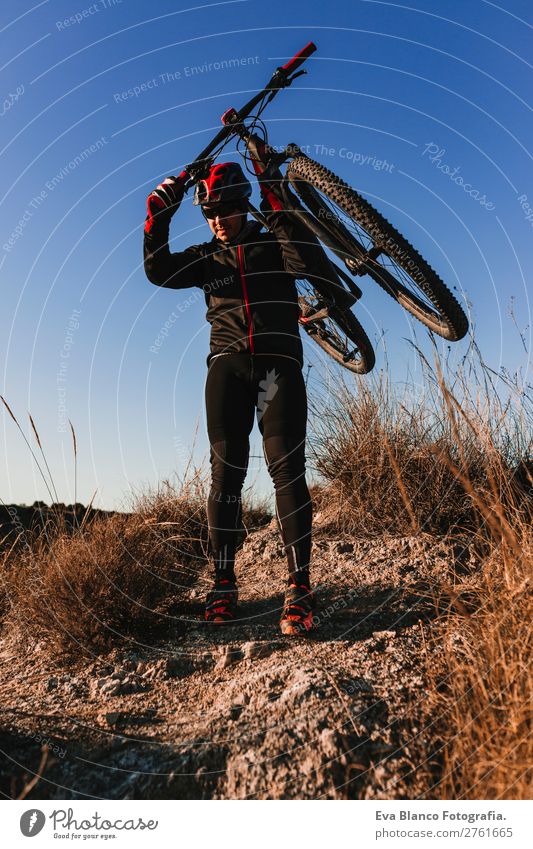 Radfahrer, der das Fahrrad bei Sonnenuntergang hält. Sportkonzept. Lifestyle Erholung Freizeit & Hobby Abenteuer Sommer Berge u. Gebirge Fahrradfahren maskulin
