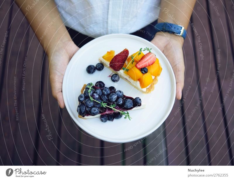 Nahaufnahme der Hände mit der Halteplatte aus Heidelbeerkuchen Käse Frucht Dessert Teller Sommer Restaurant Frau Erwachsene Hand frisch lecker weiß Hintergrund