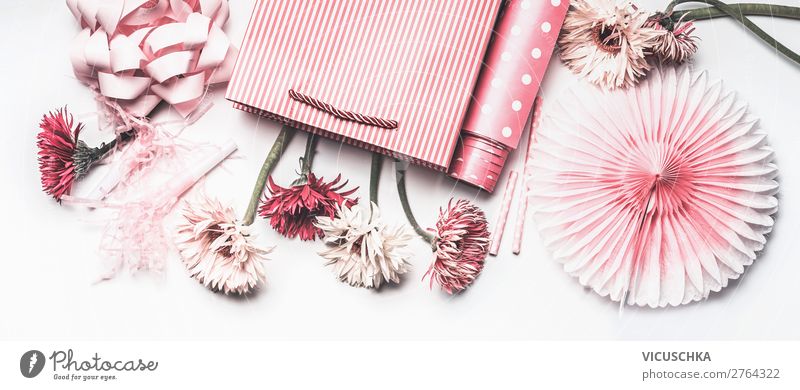 Zusammenstellung von rosa Accessoires für weibliche Feiertage: Muttertag, Frauentag, Geburtstag oder Hochzeit. Papier-Einkaufstasche mit Blumen, Papier, Partyfächer und Band auf weißem Hintergrund, Ansicht von oben