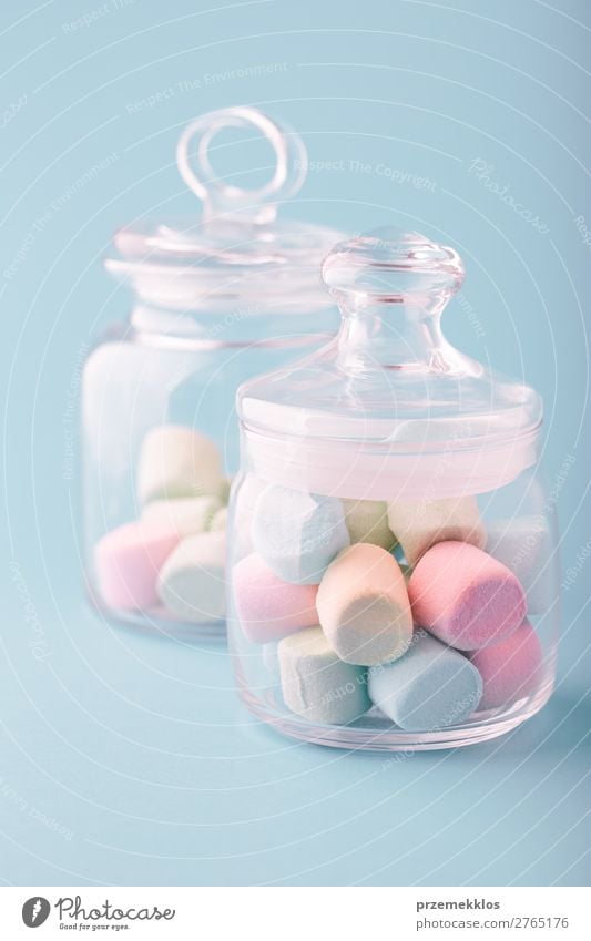 Ein mit bunten Marshmallows gefülltes Glas auf schlichtem Hintergrund. Dessert Süßwaren Ernährung Essen Diät Tisch hell lecker blau Farbe Bonbon farbenfroh