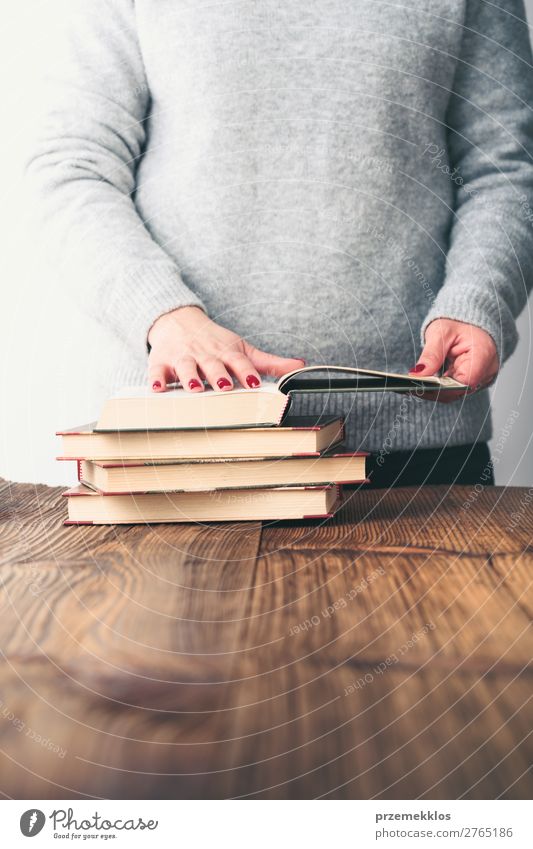 Junge Frau beim Betrachten von Buchseiten auf dem Tisch in der Buchhandlung Lifestyle kaufen Erholung Freizeit & Hobby lesen Schule lernen Mensch Erwachsene