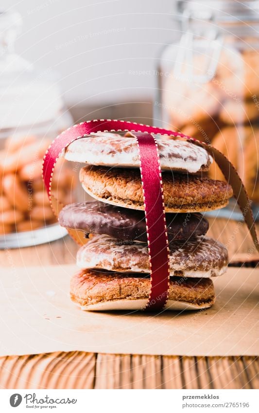 Ein paar Lebkuchenplätzchen in rotem Band auf Holztisch verpackt. Dessert Ernährung Essen Diät Glück Tisch Schnur genießen lecker braun Weihnachten backen