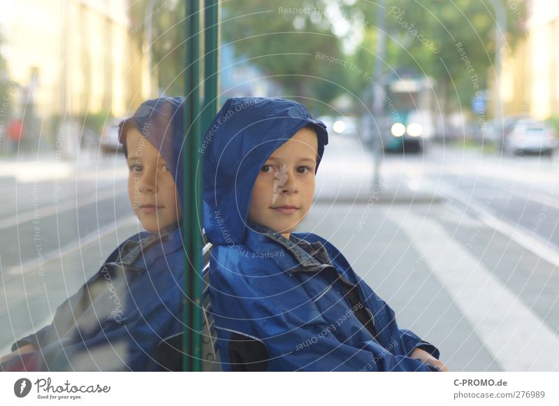 Junge mit Regenjacke sitzt an Haltestelle Mensch maskulin Kind 1 3-8 Jahre Kindheit Potsdam Stadt Bahnfahren Jacke Kapuze Lächeln warten Glück Zufriedenheit