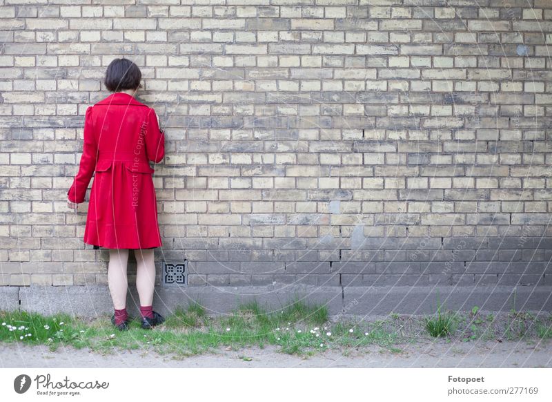 Gegen die Wand feminin Junge Frau Jugendliche 1 Mensch 18-30 Jahre Erwachsene Mauer Mantel schwarzhaarig berühren stehen rot ruhig Enttäuschung Einsamkeit Scham