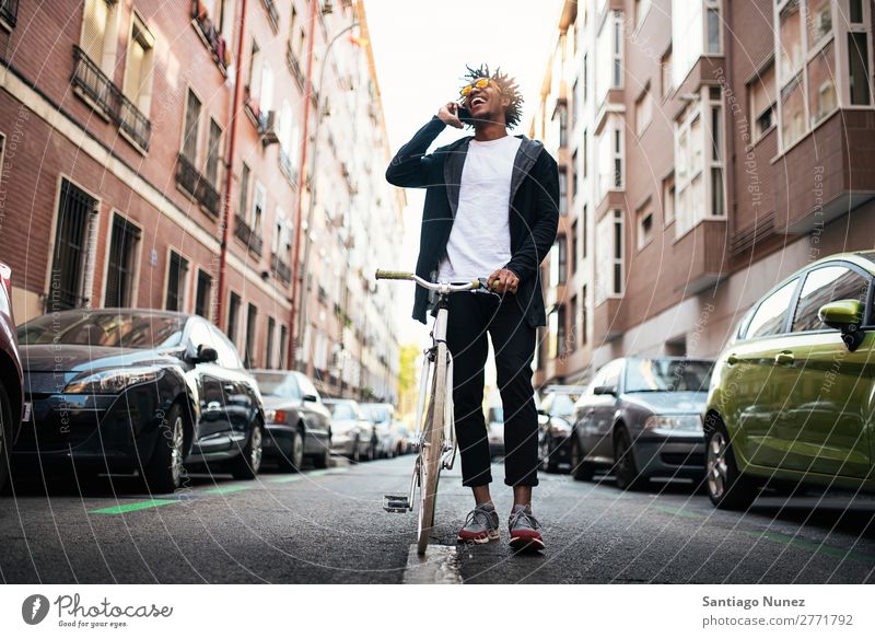 Gutaussehender junger Mann mit Handy und festem Fahrrad. Jugendliche Afrikanisch schwarz Mulatte Afro-Look Mobile Fixie Telefon Lifestyle stehen Fahrradfahren