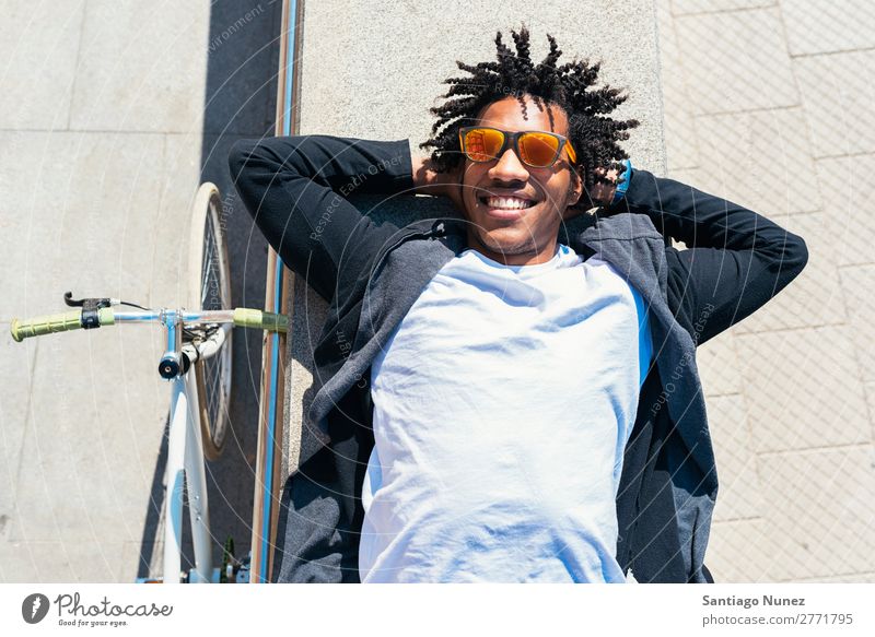 Ein gutaussehender Afro-Mann, der sich in der Nähe seines Fahrrads entspannt. Fixie Schickimicki Lifestyle laufen lügen Erholung genießend Fahrradfahren