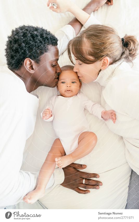 Glückliche Familie, Mutter, Vater und Baby. Junge Kind Bett Mädchen lügen neugeboren Eltern multiethnisch Afrikanisch vielfältig Liebe Küssen Mensch
