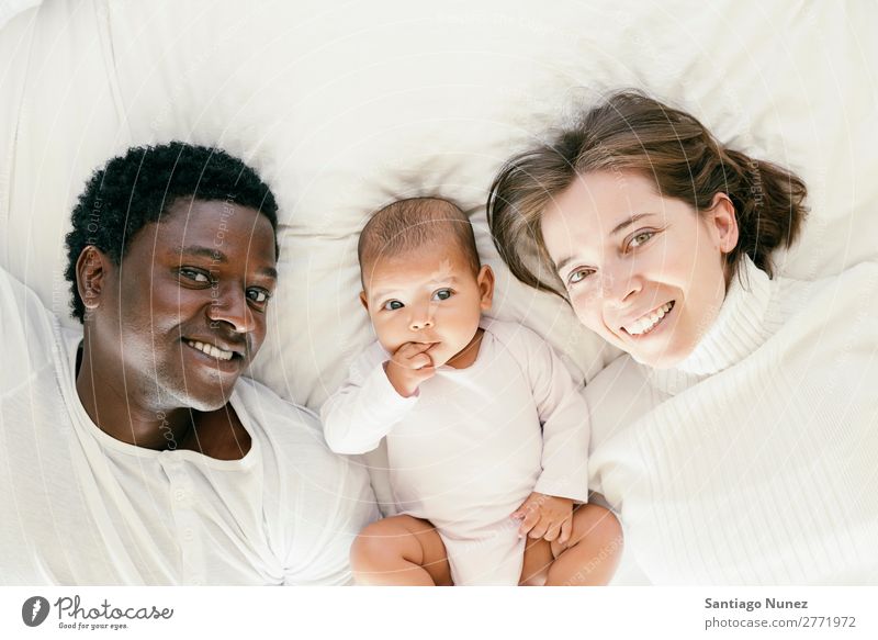 Glückliche Familie, Mutter, Vater und Baby. Junge Kind Bett Mädchen lügen neugeboren Eltern multiethnisch Afrikanisch vielfältig Mensch interrassisch Kaukasier
