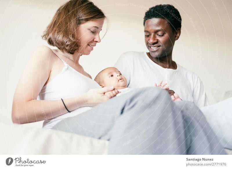 Glückliche Familie, Mutter, Vater und Baby. Junge Kind Bett Mädchen lügen neugeboren Eltern multiethnisch Afrikanisch vielfältig Mensch interrassisch Kaukasier