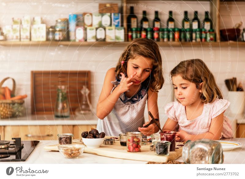 Kleine Schwestern Mädchen bereitet das Backen von Keksen vor. Kind kochen & garen Koch Küche Schokolade Verkostung Finger Speiseeis Erdbeeren Tochter Tag Glück