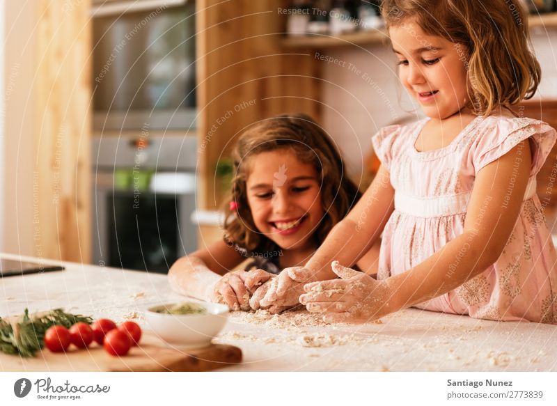 Kleine Schwestern kneten Teig und bereiten sich auf das Backen von Keksen vor. Kind Mädchen kochen & garen Koch Küche Mehl Hand Teigwaren dreckig gefärbt lachen