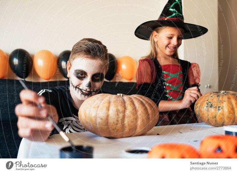 Glückliche Kinder verkleideten sich und schmückten zu Hause einen Kürbis. Halloween Mädchen Junge malen Skelett Hexe Freude Familie & Verwandtschaft Schwester