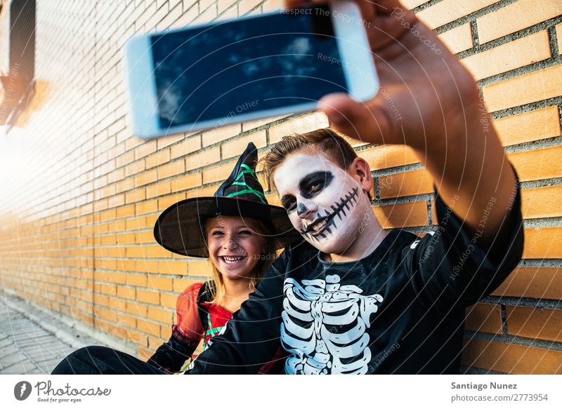 Glückliche Kinder getarnt fotografieren mit dem Telefon auf der Straße. Halloween Mädchen Junge Selfie Skelett verkleidet Mobile PDA Fotografie