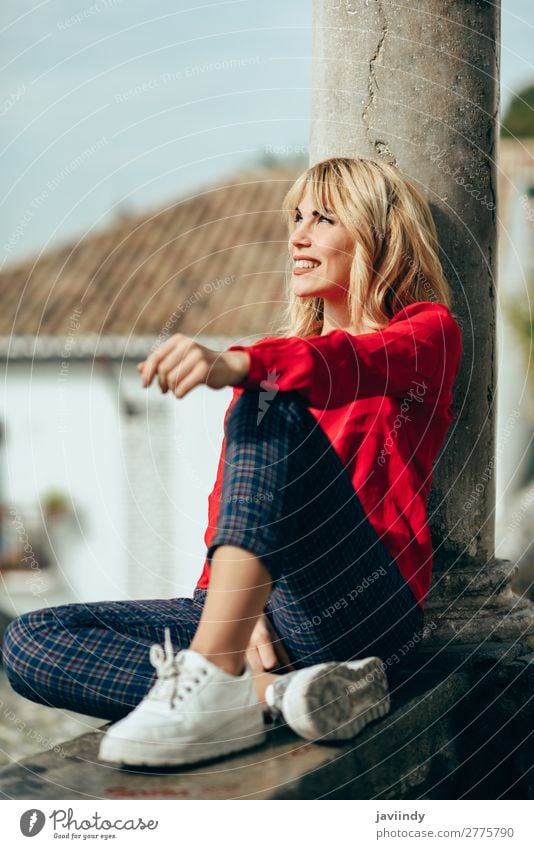 Glückliche Frau, die auf einem urbanen Hintergrund sitzt und sich sonnt. Lifestyle Stil schön Haare & Frisuren Mensch feminin Junge Frau Jugendliche Erwachsene