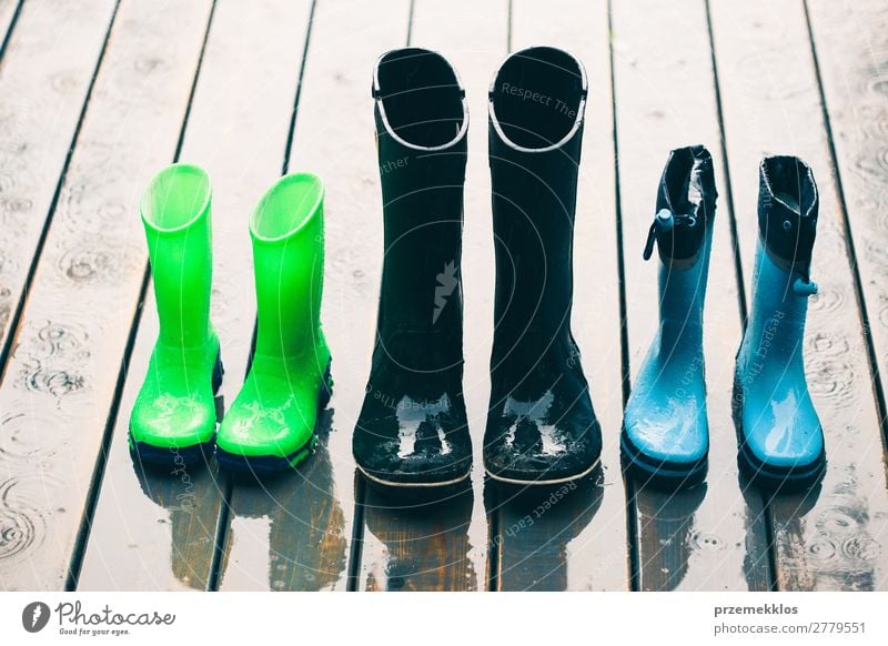 Reihe von Gummistiefeln, die auf einer Holzterrasse stehen, während es regnet. Freude Sommer Kind Mensch Frau Erwachsene Mann Wetter Regen Mantel Schuhe Stiefel