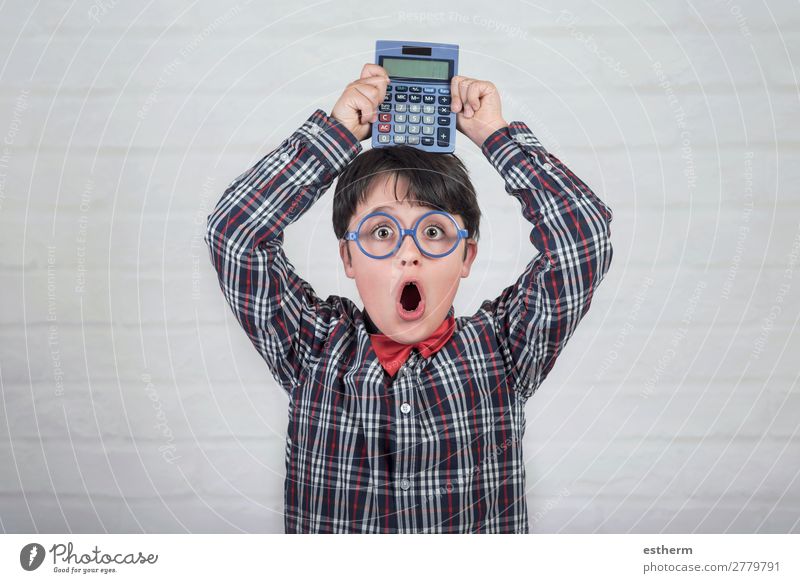 Glücklicher Student zeigt Taschenrechner über seinem Kopf vor einem Backsteinhintergrund Lifestyle Freude Kind Schule lernen Schulkind Kapitalwirtschaft