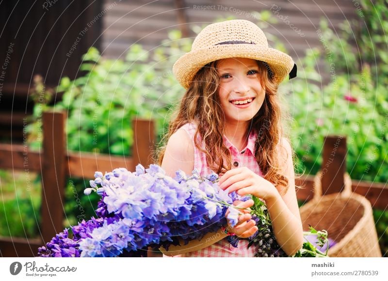 romantisches Porträt eines glücklichen Mädchens, das einen Strauß schöner blauer Rittersporn-Blumen aus dem Sommergarten pflückt Pflanze Blüte Kind spielen