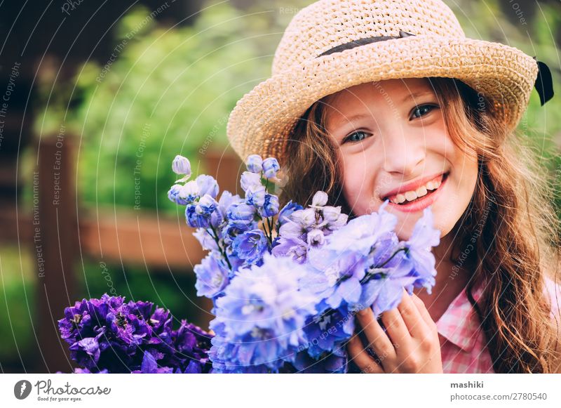 romantisches Porträt eines glücklichen Mädchens, das einen Strauß schöner blauer Rittersporn-Blumen aus dem Sommergarten pflückt Pflanze Blüte Kind spielen