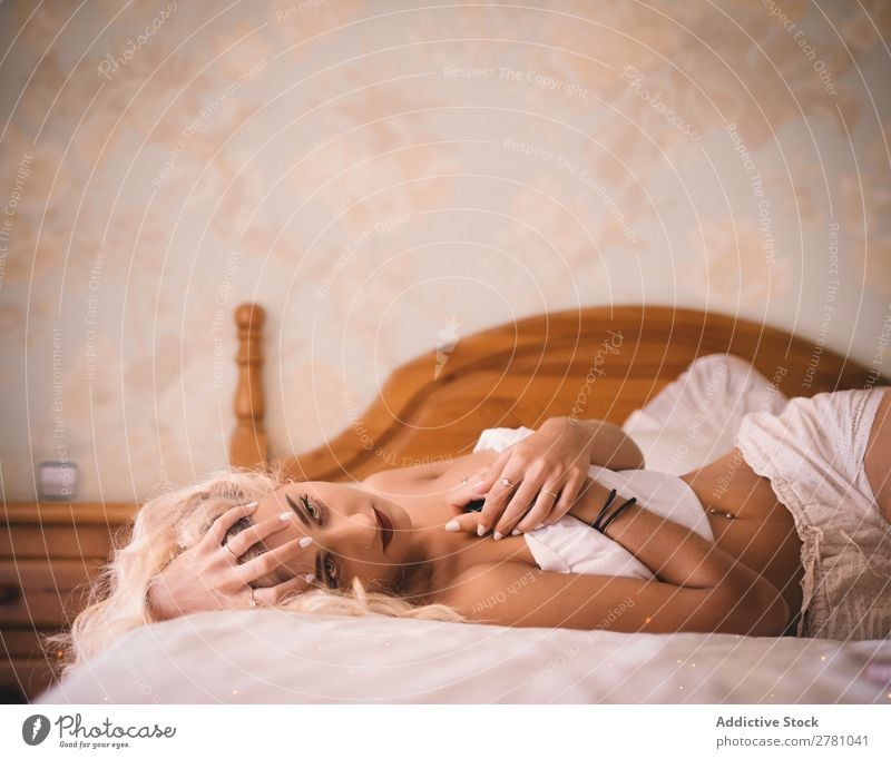 Hübsche blonde Frau, die auf dem Bett liegt und die Arme verschränkt. wunderschön Körper Entwurf dritter Arm Kopf ausgefallen Phantasie Blume Illusion niemand