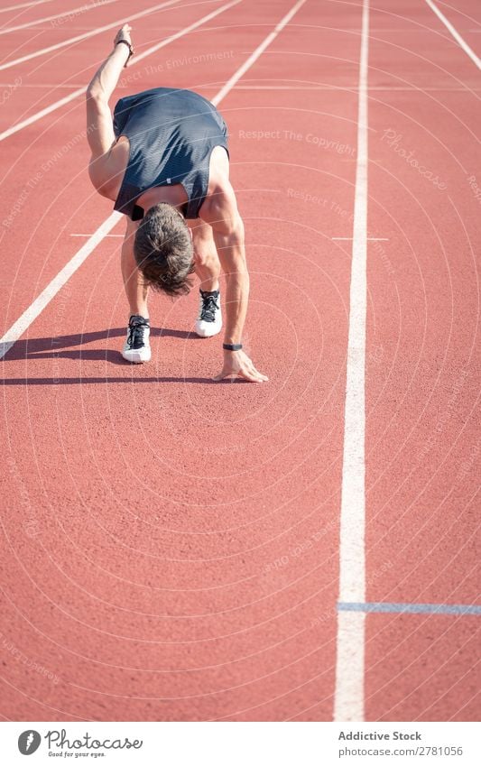 Mann in der Nähe der Planke im Stadion Sportler Läufer Rennbahn Kauerstart Sprinter Erfolg Biegen Fitness üben Athlet muskulös Erwachsene Sportbekleidung