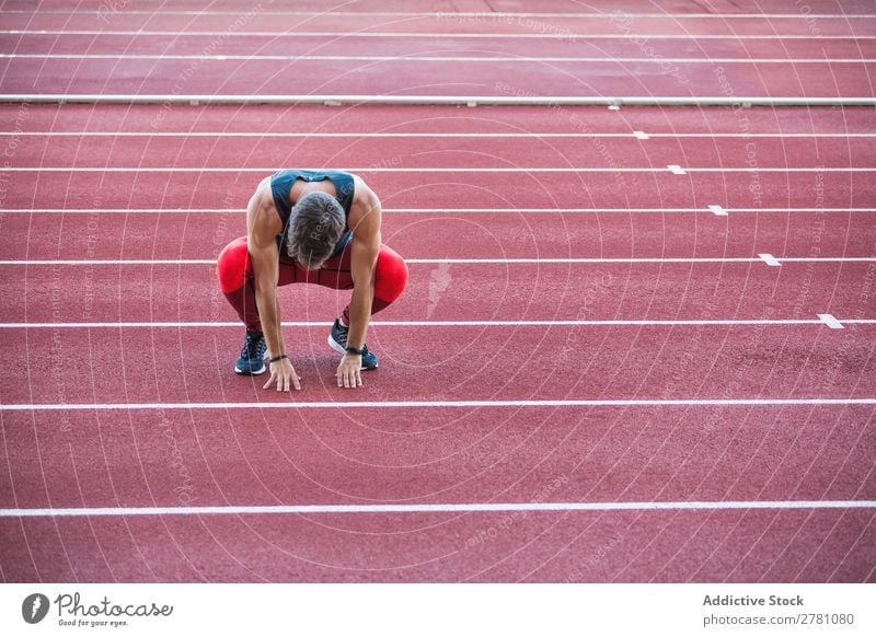 Sportler auf der Rennstrecke sitzend Mann Rennbahn ruhen Körperhaltung Kniebeuge Fitness üben Athlet muskulös Erholung Erwachsene Stadion Sprinter Pause