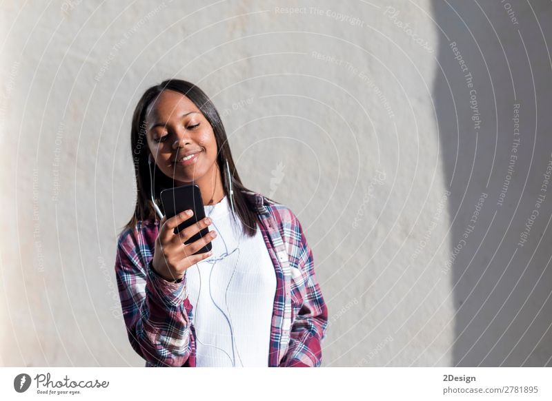Vorderansicht einer jungen lächelnden Afroamerikanerin im Stehen Lifestyle Glück schön Entertainment Musik Telefon Mensch feminin Junge Frau Jugendliche