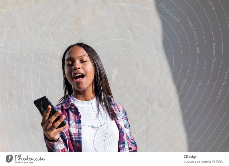 Vorderansicht einer jungen lächelnden Afroamerikanerin im Stehen Lifestyle Glück schön Entertainment Musik Telefon Mensch feminin Junge Frau Jugendliche