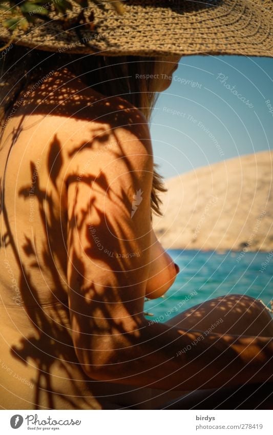 barbusige Frau mit Strohut beim FKK-Urlaub am Mittelmeer. Schattenwurf von Gewächsen auf nackter Haut exotisch Wohlgefühl Sommerurlaub Sonnenbad Meer Junge Frau